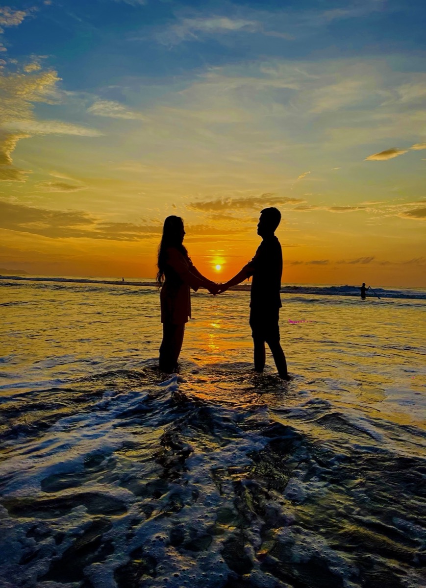 Hai vợ chồng nắm tay nhau đón hoàng hôn trên biển